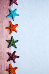 Fototapeta na wymiar Six colorful starfishes on a blue-pink background