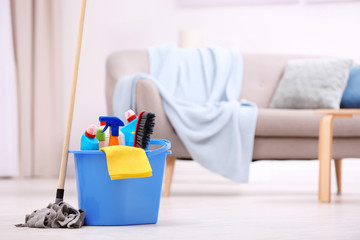 Bucket with cleaning supplies on floor indoors. Space for text