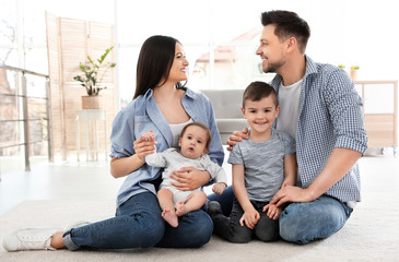 Happy couple with children sitting on floor at home. Family weekend