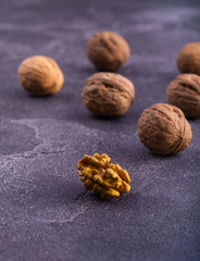 Whole and cracked walnuts on blue textured surface, side view. Healthy nuts and seeds.