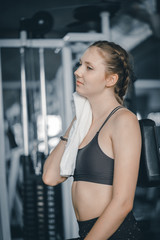 Young attractive woman caucasian sitting and using towel to wipe the sweat. Relaxation after hard workout in gym. Fitness concept, Healthy, Sport, Lifestyle