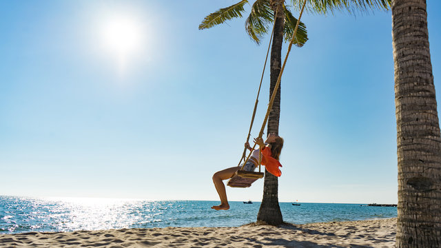 Vacation concept. Young woman swing on a beach swing. Happy traveller women on the Phu Quoc beach