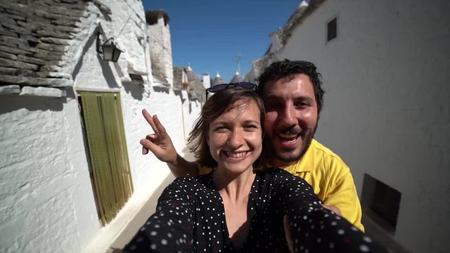 Tourists couple visiting typical town of Apulia region with trulli typical buildings unique in the world