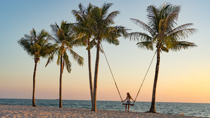 Obraz na płótnie Canvas Vacation concept. Young woman swing on a beach swing. Happy traveller women on the Phu Quoc beach