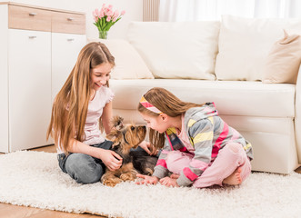 Two girls playing with yorkie