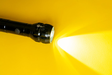 steel torch isolated on yellow surface, producing light beams or rays, copy space b