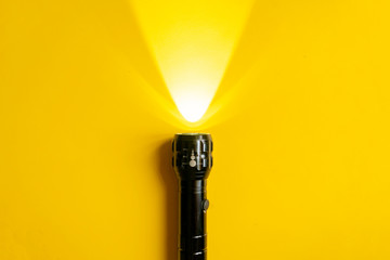 steel torch isolated on yellow surface, producing light beams or rays, copy space b