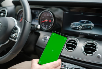 Fototapeta na wymiar Man using smartphone on the background of a luxury class car dashboard