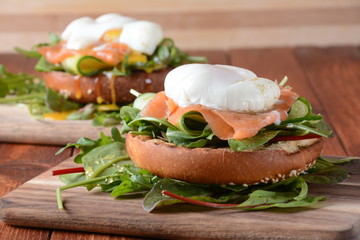 Poached egg with green cucumber, arugula beet leaves , smoked salmon and spices on a toast, wooden background. Healthy French breakfast concept 
