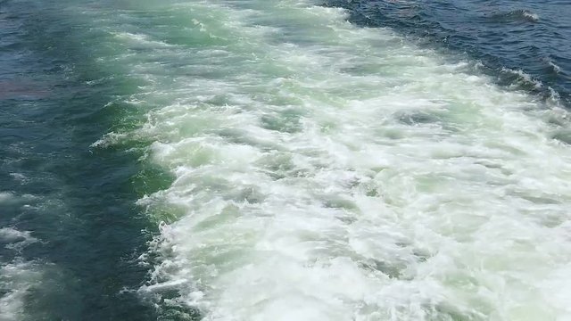 Slow motion video of Blue sea water with boat trace. There is foam and waves behind the ship. It is Atlantic ocean near the coast of Africa, Senegal. The water is clear and turqoise.