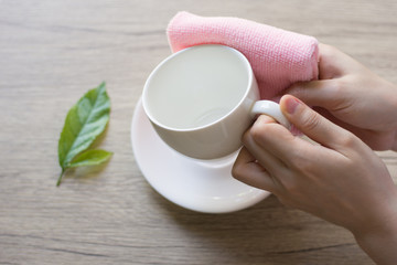 Close up woman hand cleaning coffee cup on the morning with microfiber cloth,Close up woman hand cleaning coffee cup on the rustic wood table.