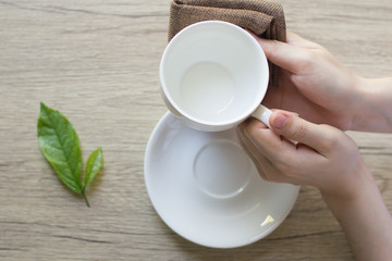 Close up woman hand cleaning coffee cup on the morning with microfiber cloth,Close up woman hand cleaning coffee cup on the rustic wood table.