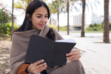 Fototapeta premium Focused pretty woman reading copy book and studying outdoors