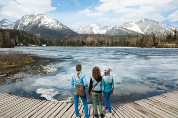 Back view on three female tourists staying by frozen mountain la