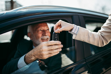 Young woman car dealer gives the keys to the new owner. Hands with keys close up.