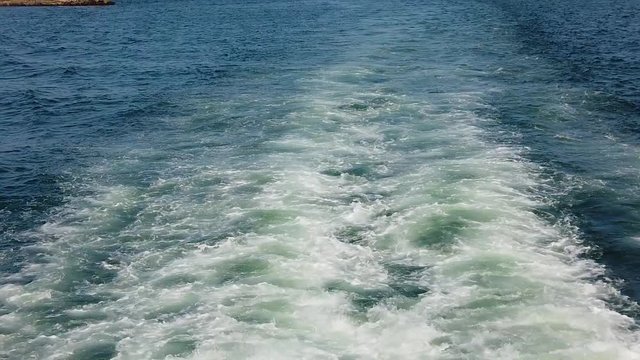 Slow motion video of Blue sea water with boat trace. There is foam and waves behind the ship. It is Atlantic ocean near the coast of Africa, Senegal. The water is clear and turqoise.