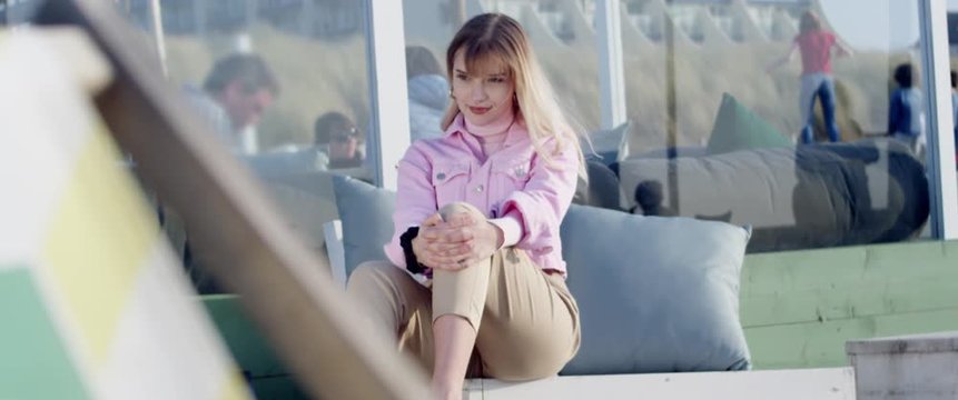 Junge h&uuml;bsche Frau sitzt in einer Bar am Strand von Schevening in Holland