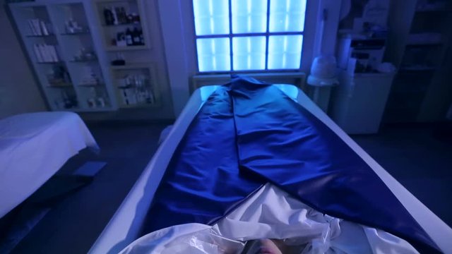 A young happy girl enjoys the procedure of hydro massage and wraps with chromotherapy in a modern cosmetic clinic. Body care.