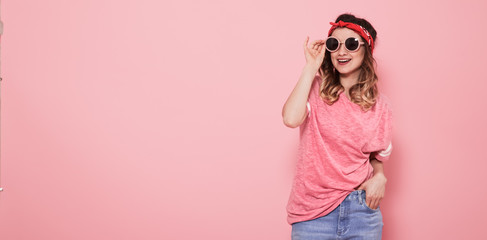 Portrait of hipster girl in glasses on pink background