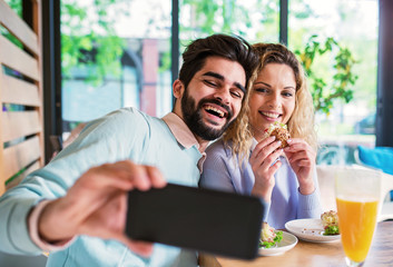 Beautiful young couple sitting in a cafe, having breakfast. Love, dating, food, lifestyle concept
