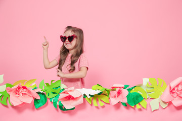 Portrait of a little girl with sunglasses on a pink background