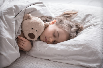 Fototapeta na wymiar Little cute girl in bed with toy