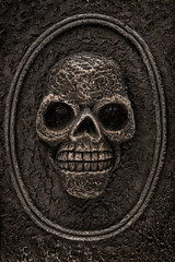 Close up on a skull in a medallion on a tombstone. Halloween decoration concept.