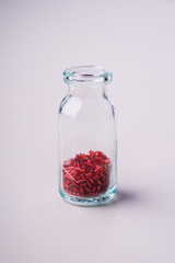 Red color beads in transparent bottle white background