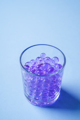 Purple marbles in drinking transparent glass blue background