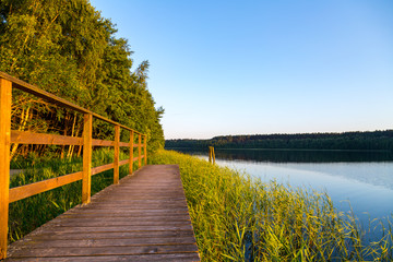 ein See mit Holzsteg umgeben von Wald	