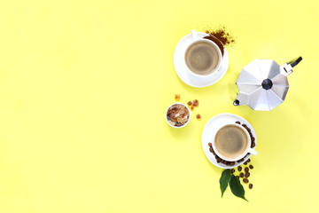 Two cups of espresso . Coffee beans, ground coffee on yellow background