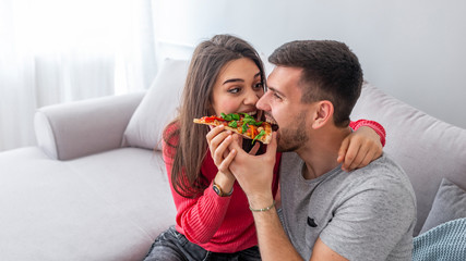 Indoor portrait of girl and her boyfriend eating pizza. Laughing couple relaxing in weekend. Couple...