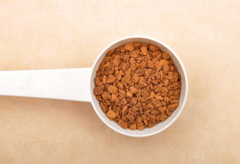 Löslicher Kaffee mit Dosierlöffel auf braunem Hintergrund