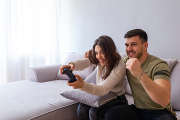Obraz premium Young people having fun with new technology console online - Happiness and gaming concept. Photo of young couple playing video games at home .
