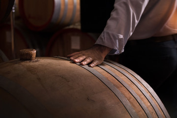 wooden barrel on a dark background, hand strokes the barrel, reverent attitude to work.
