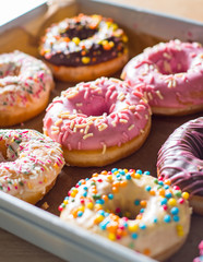 Assorted sweet donuts in a paper box.