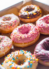 Assorted sweet donuts in a paper box.