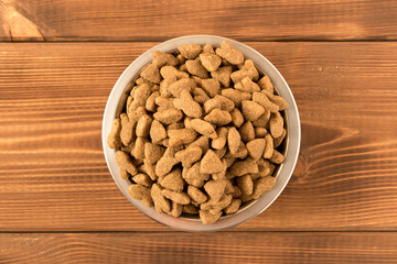 Bowl with dog food on a wooden table. Close up.