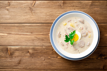 Traditional polish soup Zurek on wooden table. Top view. Copy space.