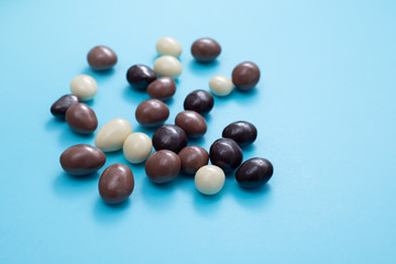 close up of chocolate egg and candy drops on blue background