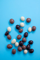 close up of chocolate egg and candy drops on blue background