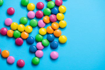 close up of chocolate egg and candy drops on blue background