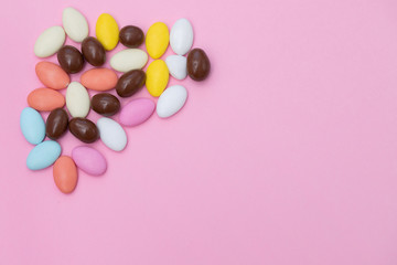 Obraz premium close up of chocolate egg and candy drops on pink background