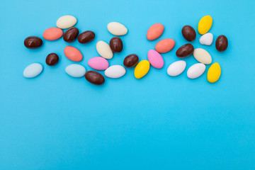 close up of chocolate egg and candy drops on blue background