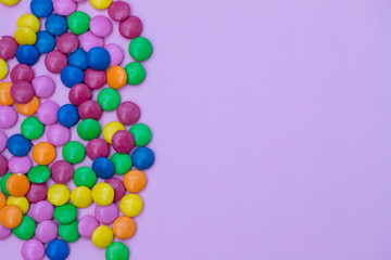 close up of chocolate egg and candy drops on pink background
