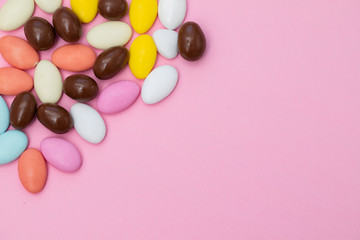 close up of chocolate egg and candy drops on pink background