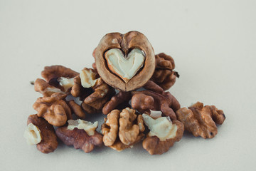  Walnuts peeled and in a shell on a white background. Half walnut in the shape of a heart.