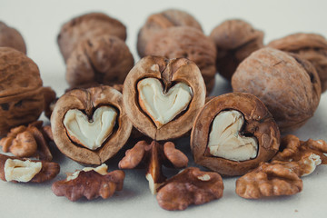  Walnuts peeled and in a shell on a white background. Half walnut in the shape of a heart.