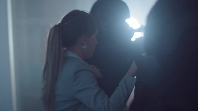 Masked Squad of Armed SWAT Police Officers Rescue a Female Hostage in a Dark Seized Office Building with Desks and Computers. Soldiers with Rifles and Flashlights Move Forwards and Cover Surroundings.