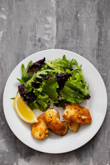fried squid with salad and lemon on white plate on ceramic dish